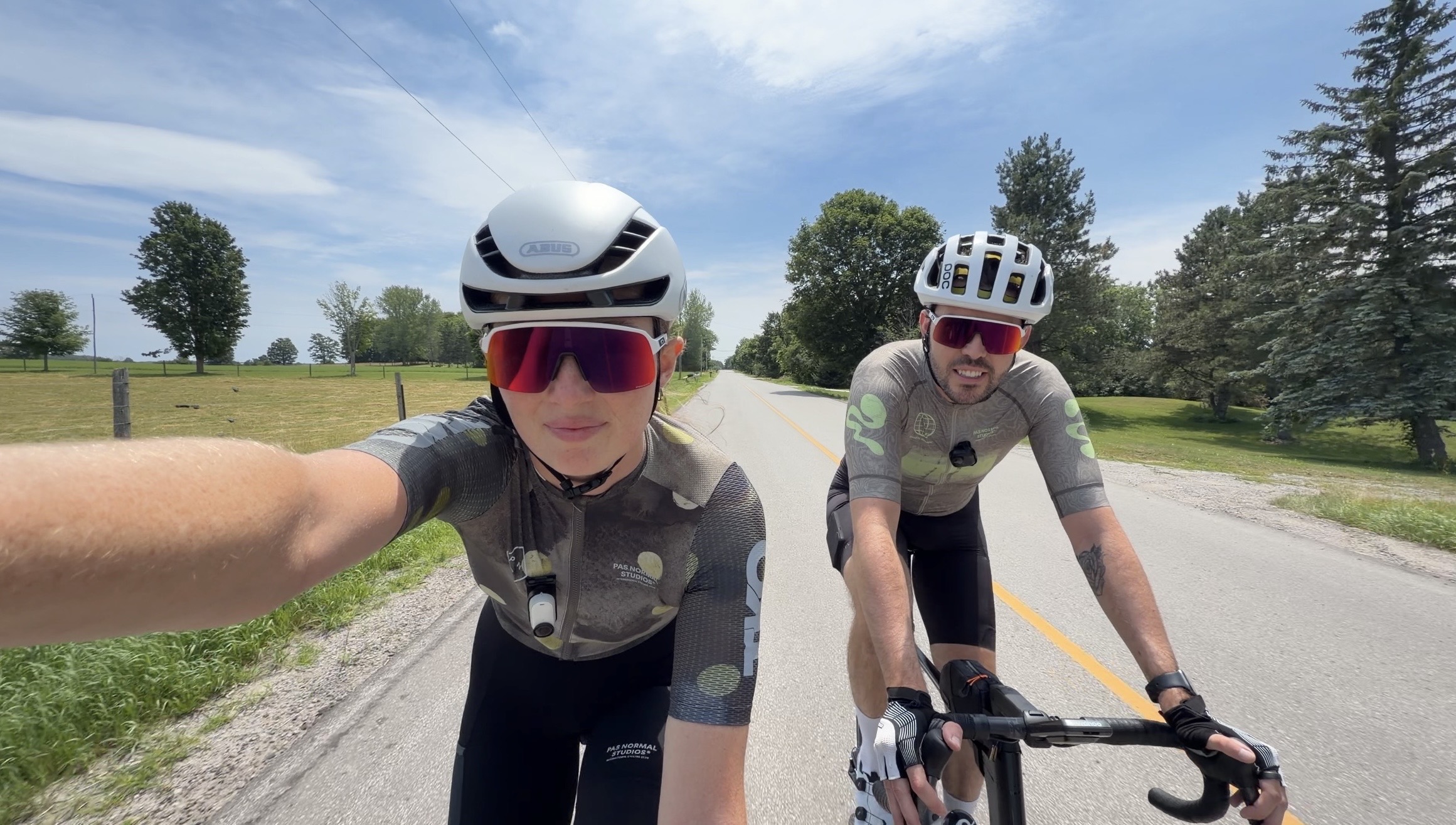 Bailey and Francis riding side by side down an open country road under a blue sky