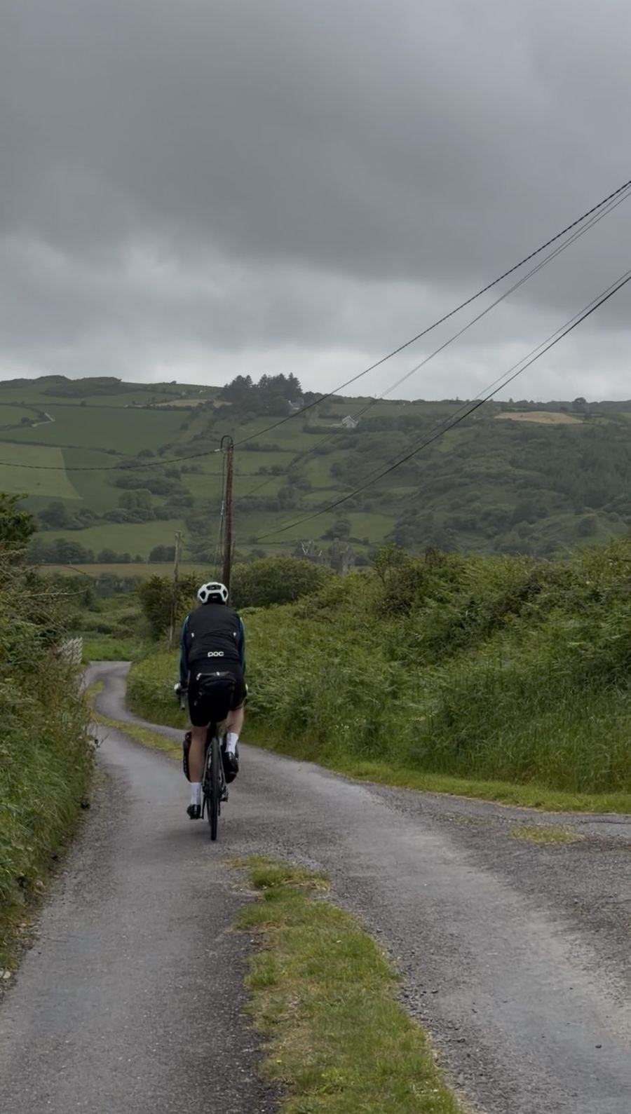 A rider climbing a narrow green country lane in West Cork with a ruined tower in the distance