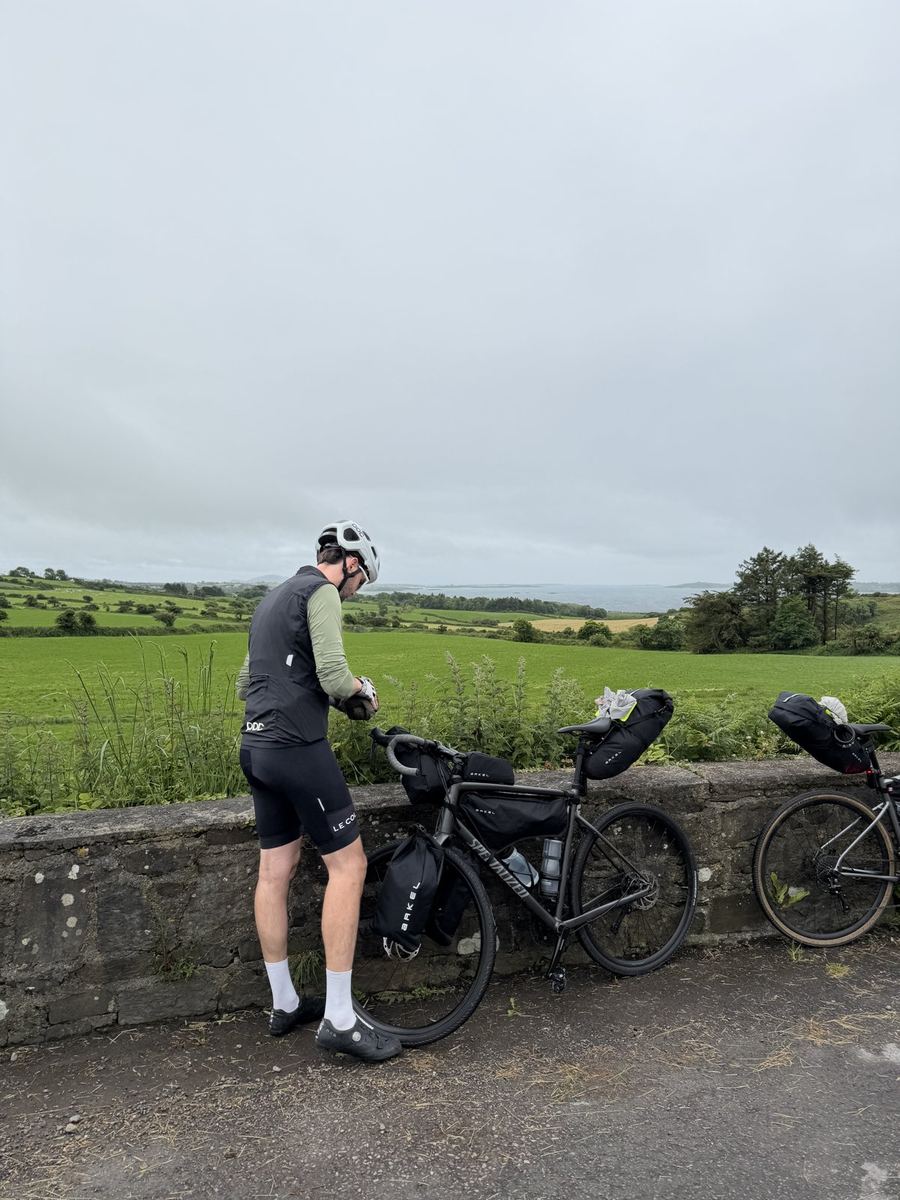 Francis stopped at his loaded bike on a stone bridge over green West Cork fields with the sea in the distance
