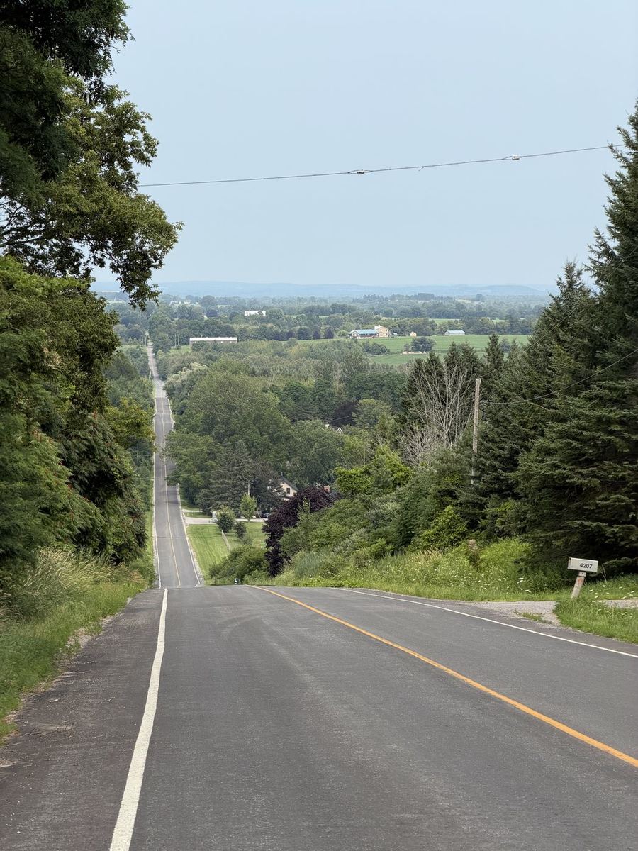 A long straight road dropping away over rolling farmland toward the horizon