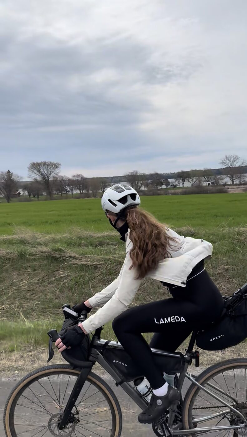 Bailey riding a quiet farm road past a green field with the lake behind